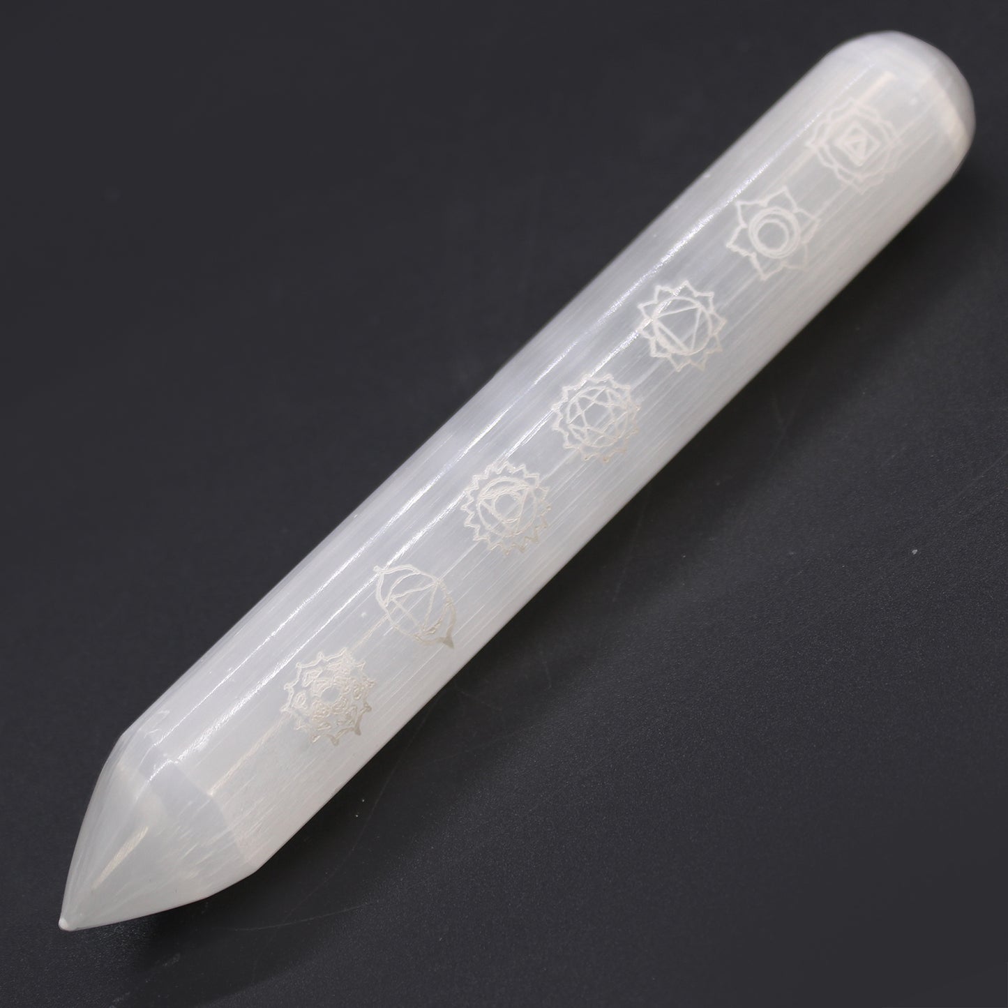 Polished Selenite wand engraved with 7 chakra symbols and a pointed tip, ideal for energy alignment, chakra healing, and spiritual cleansing rituals.