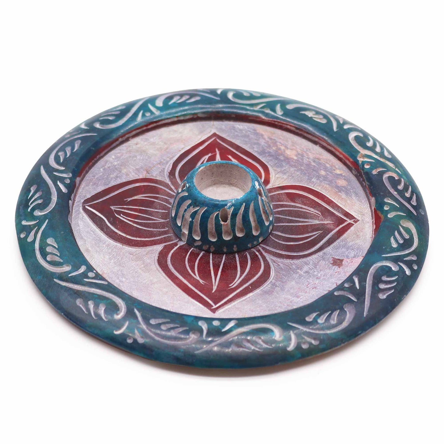 Round soapstone incense holder with carved four-petal flower design, dyed in teal and burgundy, holds both incense cones and sticks.