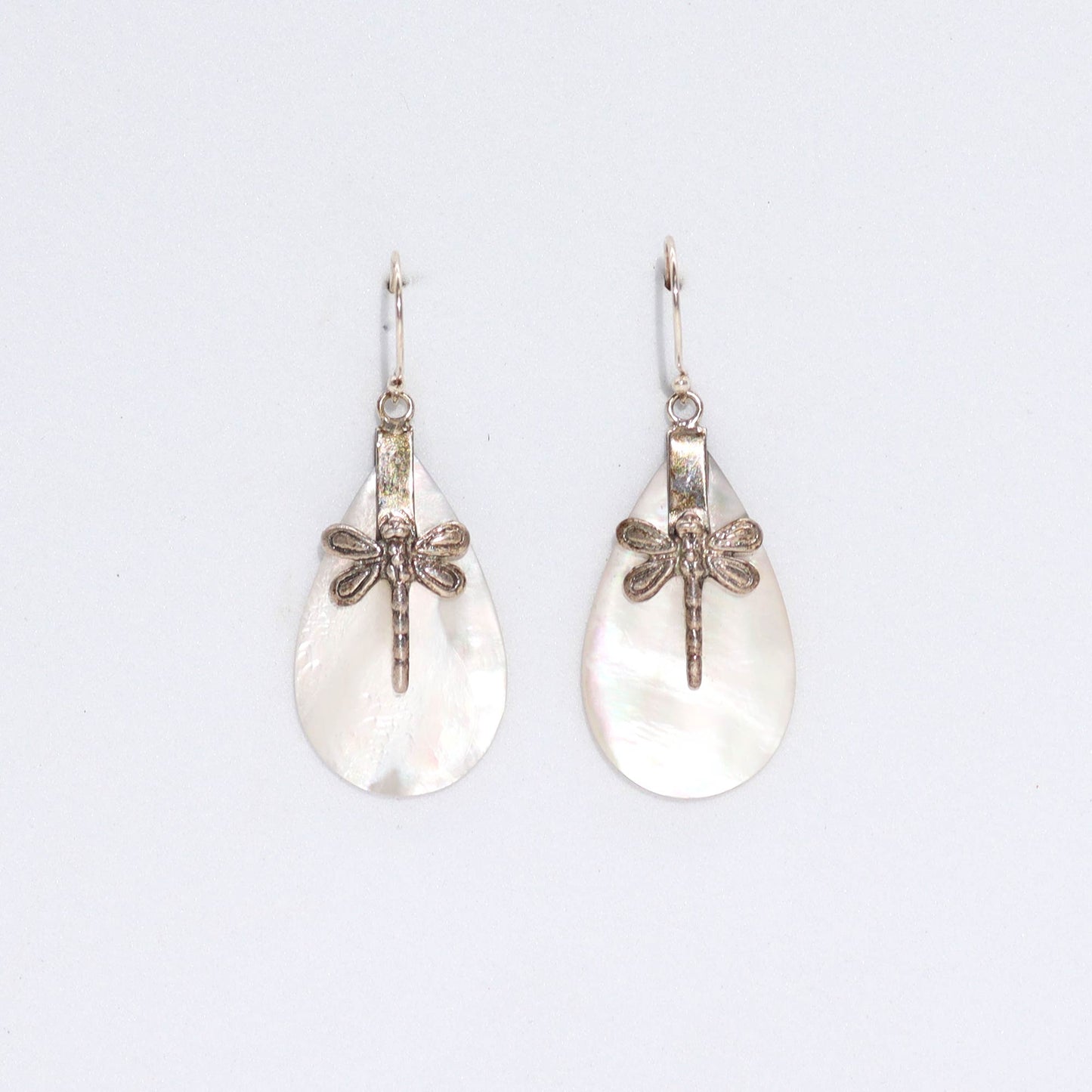 "Teardrop mother of pearl earrings with detailed silver dragonfly overlay, handcrafted in Bali."