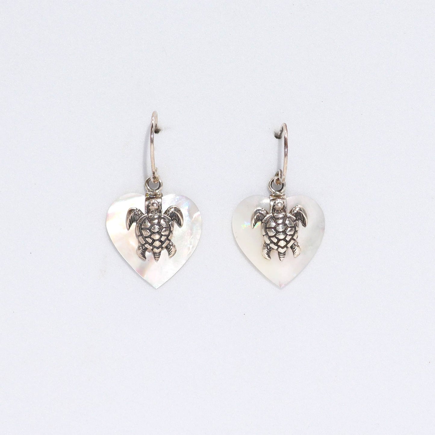 "Heart-shaped mother of pearl earrings with ornate sterling silver sea turtle overlay, handcrafted in Bali."