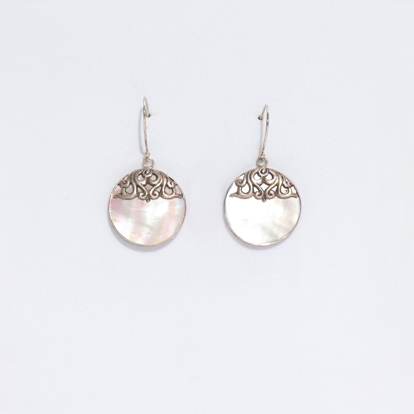 "Round mother of pearl earrings with ornate sterling silver swirl overlay and silver frame, handmade in Bali."