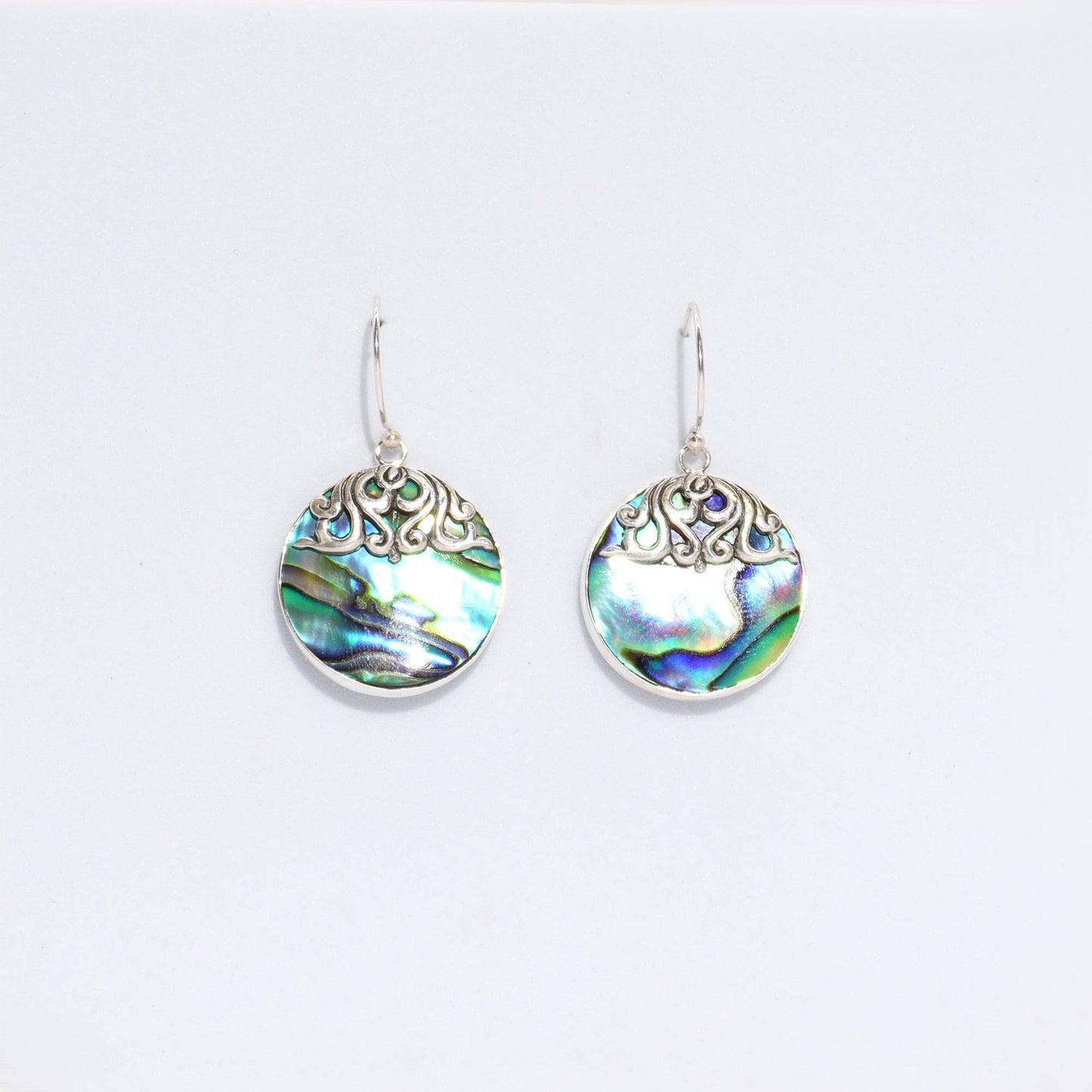 "Round abalone shell earrings with silver border and intricate swirl overlay at the top, handcrafted in Bali."