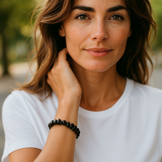 Black Agate chip stone bracelet with deep black stones, worn by a woman with brown hair and a white shirt, symbolising protection, grounding, and emotional resilience.