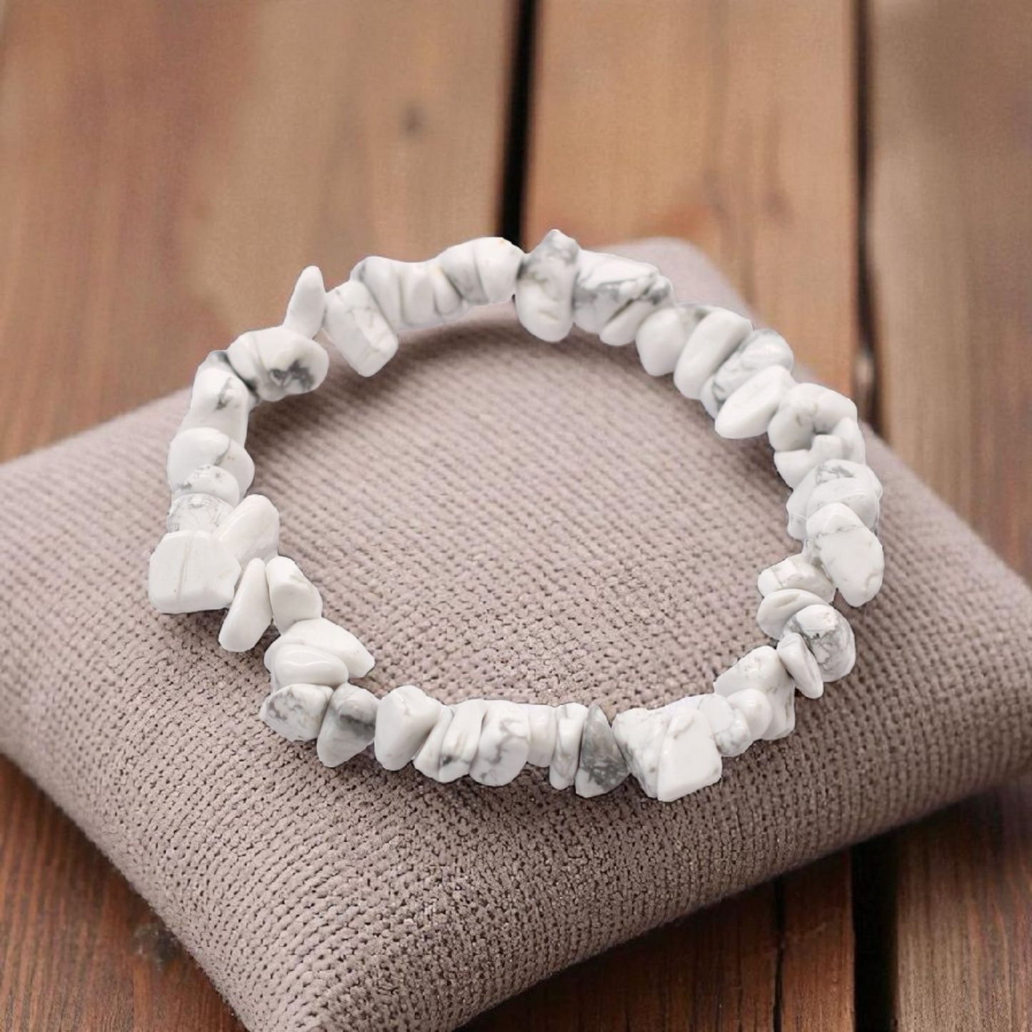 White Jasper chip stone bracelet with soft creamy stones, on a pillow on a wood table, symbolising peace, clarity, and emotional balance.