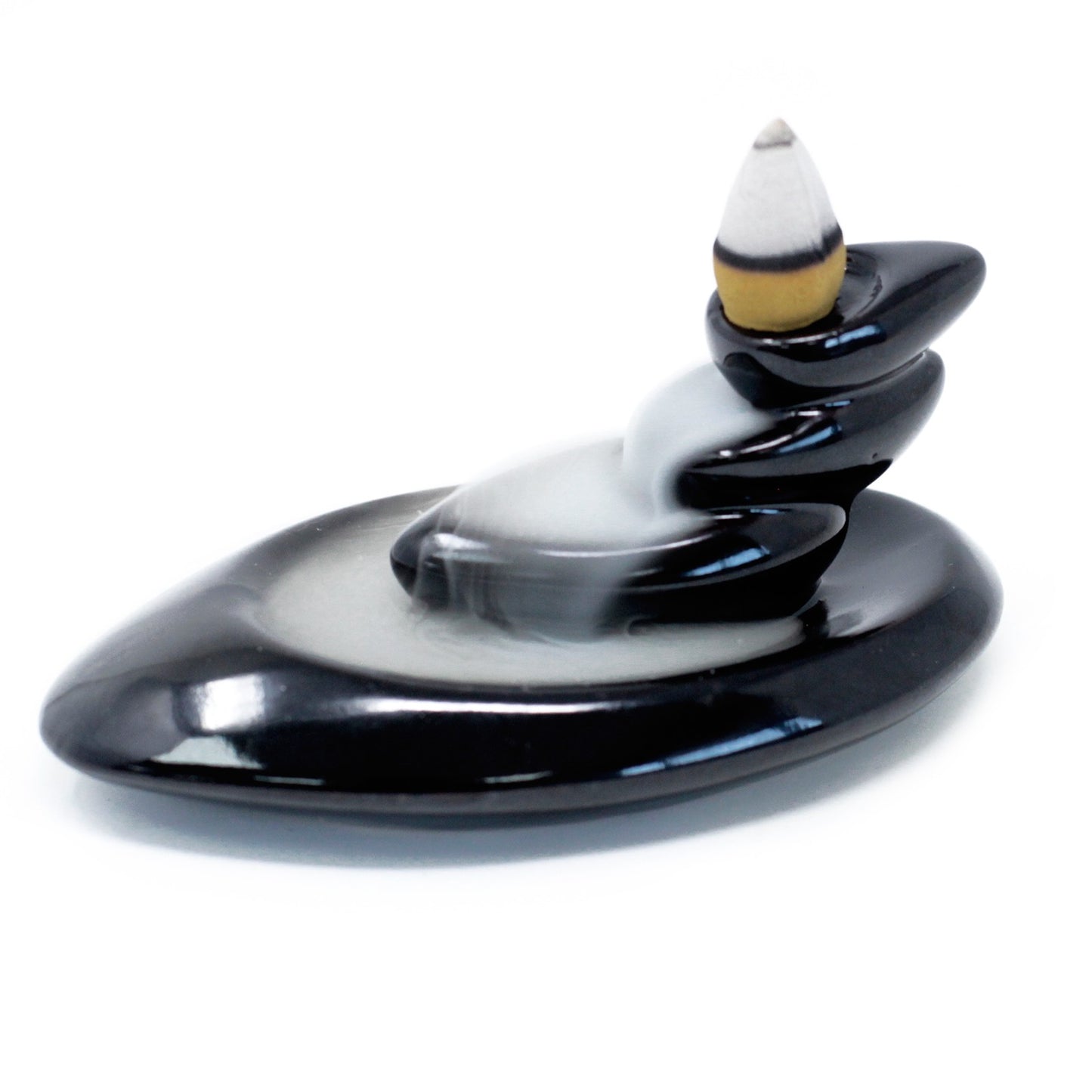 Small pebble-style backflow incense burner with cascading smoke trail, perfect for desks or minimalist meditation corners.