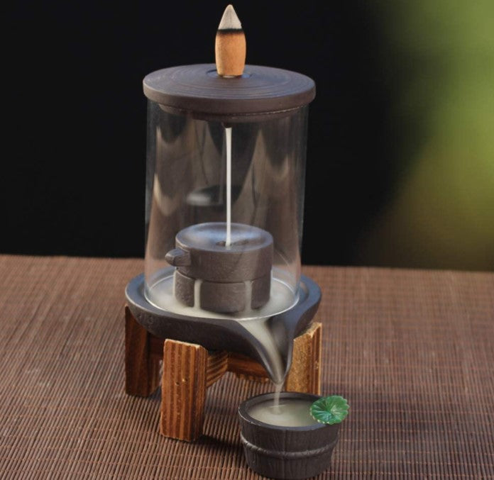 Teahouse-themed incense burner with cascading smoke from rooftop to base. Evokes Eastern serenity and traditional décor.
