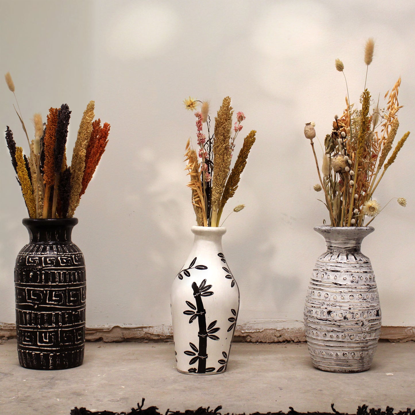 Natural terracotta vase with curved shape and black bamboo design – handcrafted in Lombok for dried flowers or decorative use.