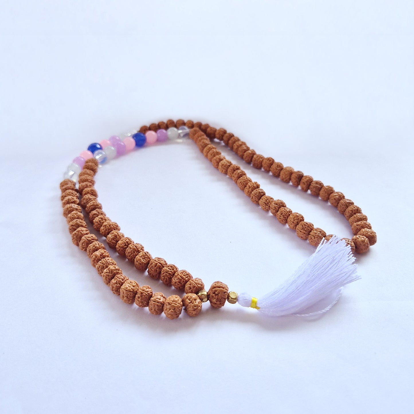 "Beauty Goddess Mala necklace with Rudraksha beads and soft-toned glass accents in pink, white, and blue, finished with a white tassel."