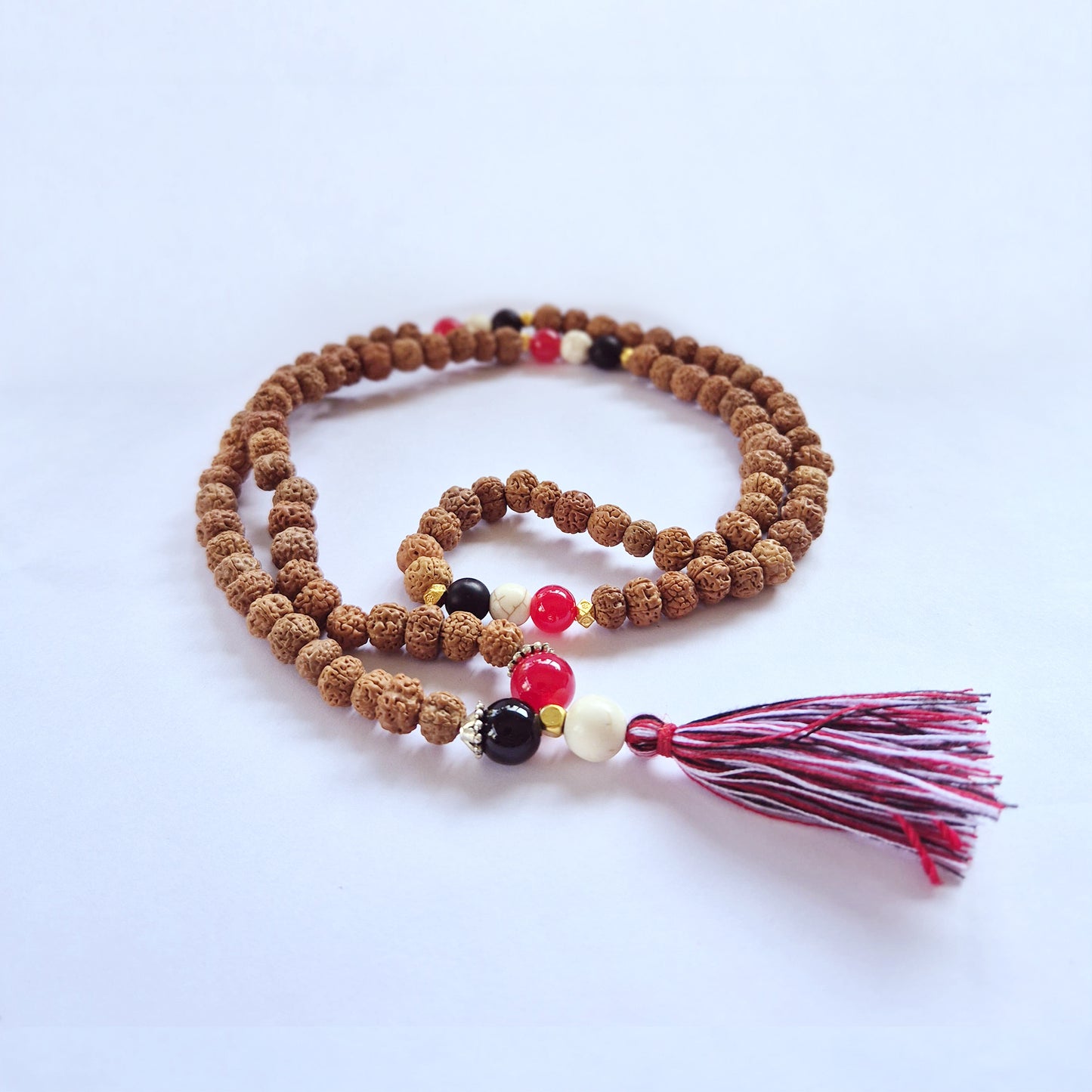 "Harmony & Protection Mala with Rudraksha beads and red, white, and black accents symbolising Tri Datu, finished with a three-colour tassel."