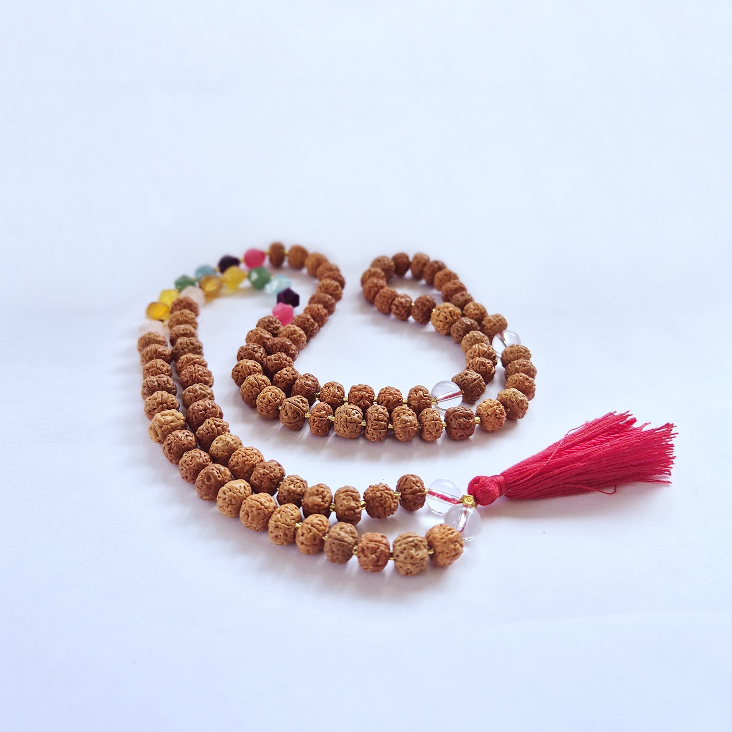 "Creativity Chakra Mala necklace with Rudraksha beads and seven chakra-coloured glass beads, finished with a bold red tassel."