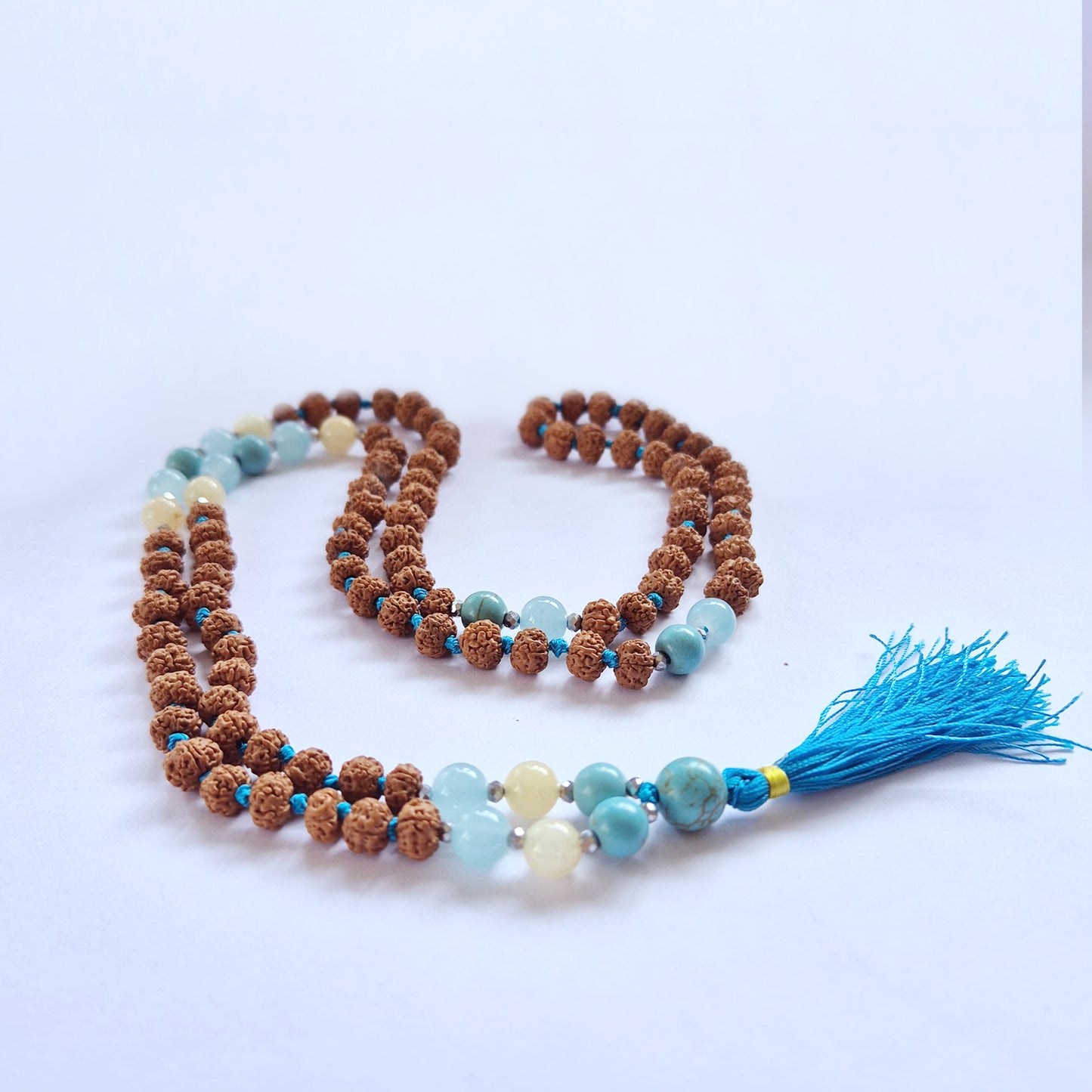 "Fertility & Abundance Mala necklace with Rudraksha and vibrant blue-toned glass beads and bright blue tassel."