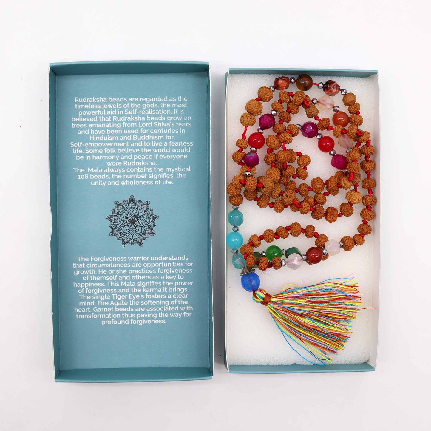 "Forgiveness Warrior Mala with Rudraksha beads, multicoloured gemstone accents, and rainbow tassel, displayed beside blue gift box."
