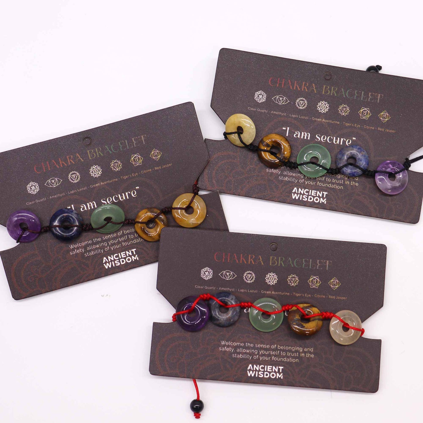 Chakra string bracelet with large donut-shaped gemstone beads and “I am secure” affirmation on adjustable cotton cord.