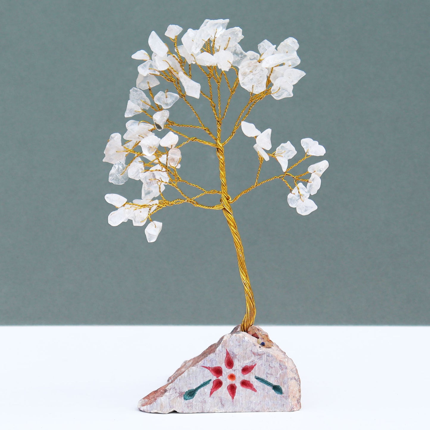 Rock quartz crystal tree with 80 clear gemstone chips on silver wire branches, displayed on a carved and painted natural stone base handcrafted in India.