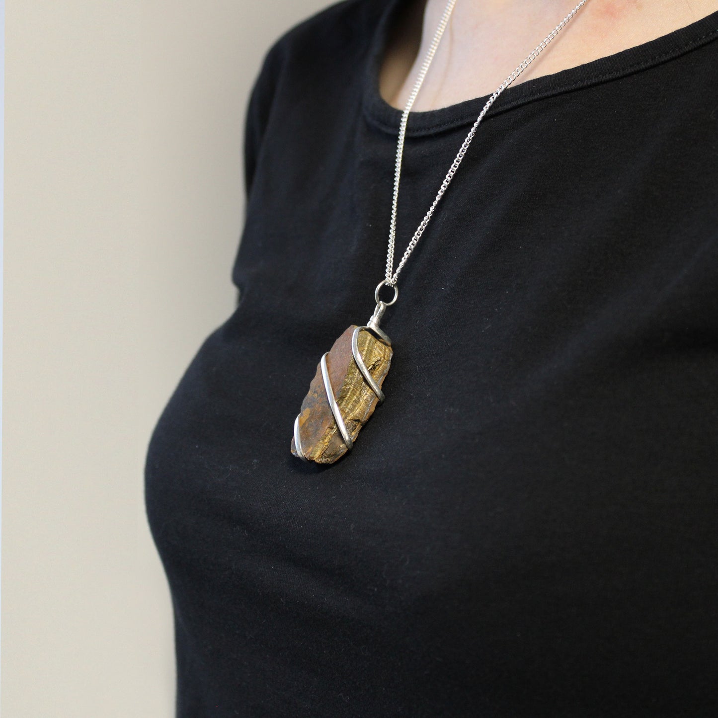 Raw Tiger’s Eye gemstone pendant with silver-toned cascading wire wrap
