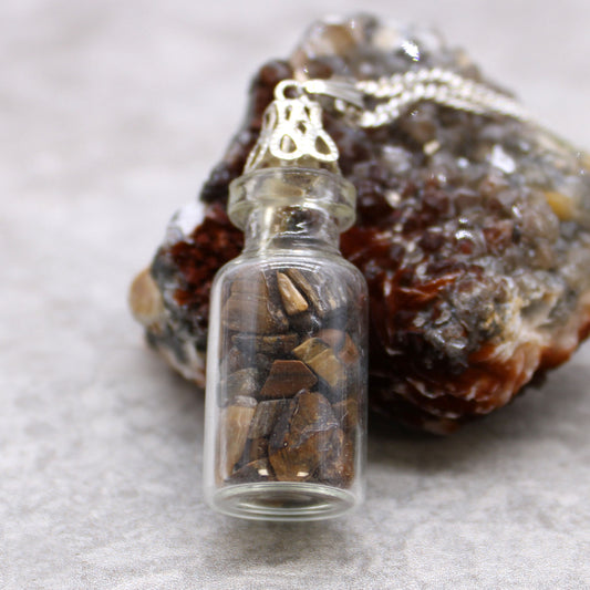 "Mini glass bottle necklace filled with golden-brown tiger’s eye chips, on a silver-plated chain"