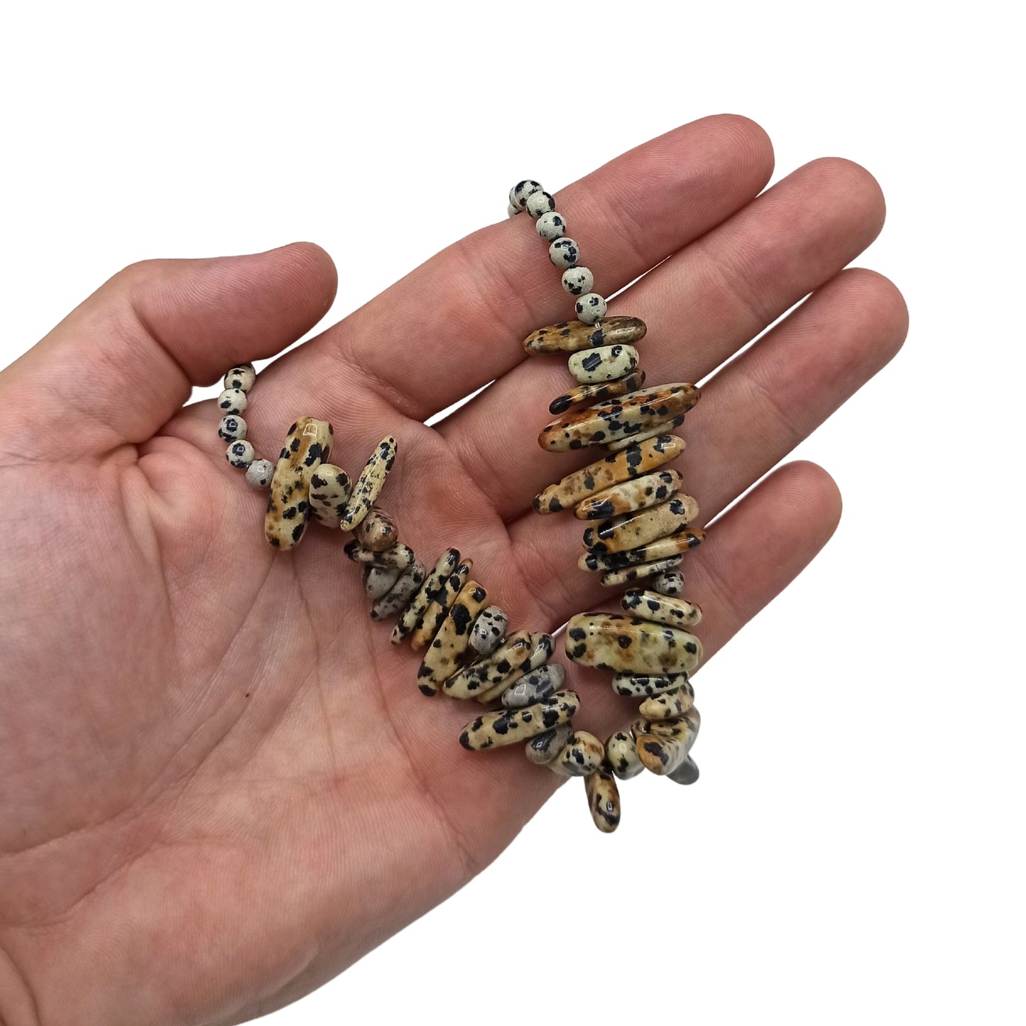 "Longstone Gem Necklace with Dalmatian Stone gemstone chips and round beads featuring natural black spots on a cream base, displayed in hand."