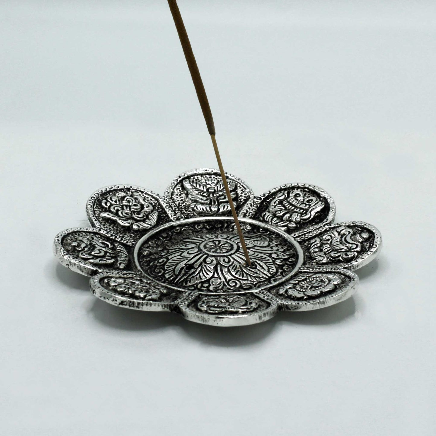 Round polished aluminium incense holder with Tibetan symbols and floral shape, 12cm in size. Suitable for incense sticks and cone incense.