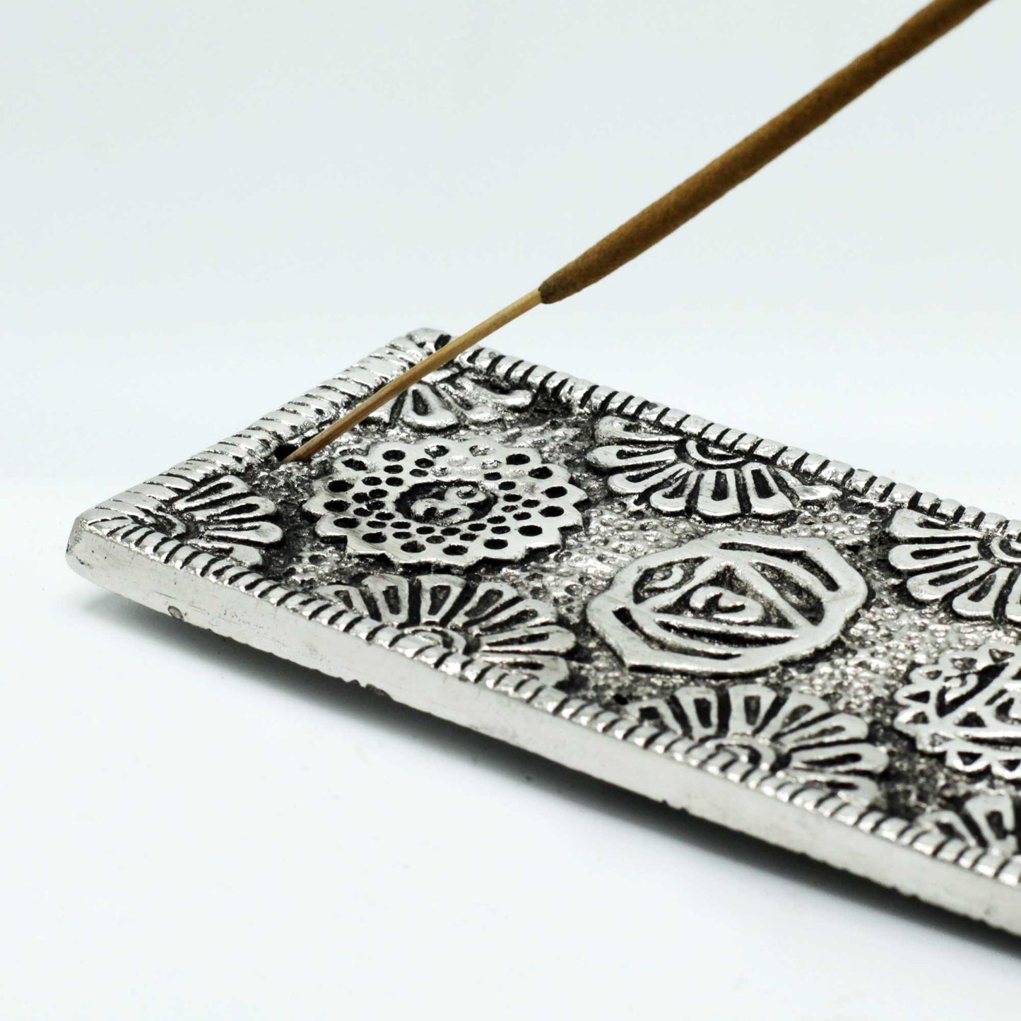 Polished aluminium incense holder with engraved chakra symbols and floral mandala patterns. 23cm long, ideal for stick incense and chakra-themed décor.
