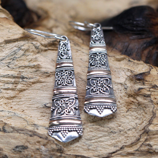"Elongated tribal-style earrings with ornate sterling silver patterns and horizontal 18k gold banding, handcrafted in Indonesia."