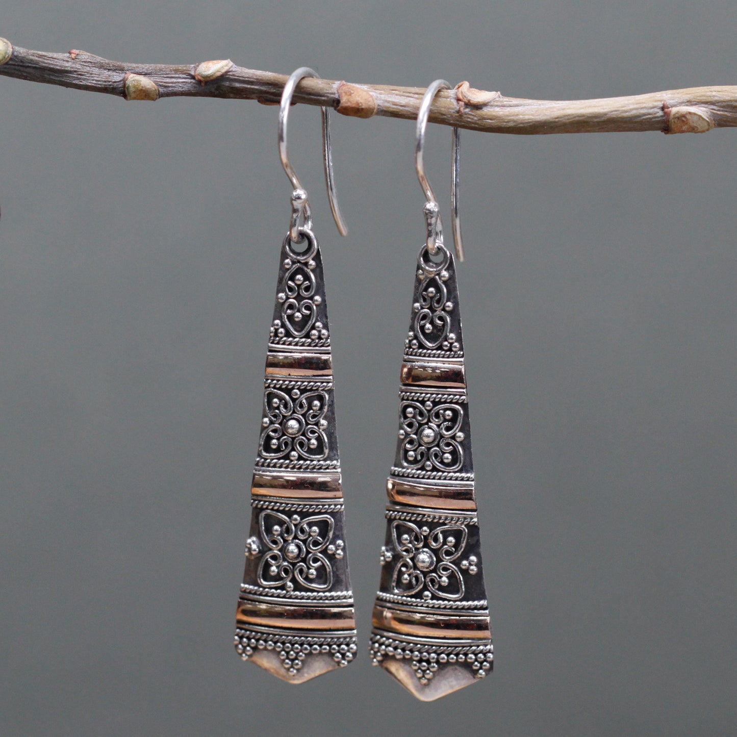 "Elongated tribal-style earrings with ornate sterling silver patterns and horizontal 18k gold banding, handcrafted in Indonesia."