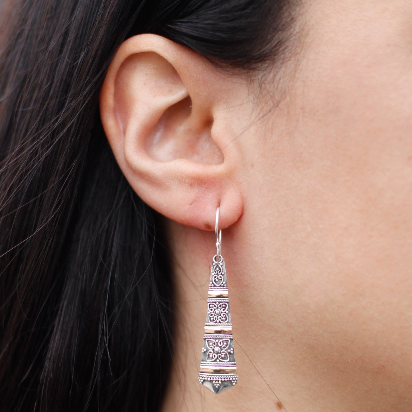 "Elongated tribal-style earrings with ornate sterling silver patterns and horizontal 18k gold banding, handcrafted in Indonesia."
