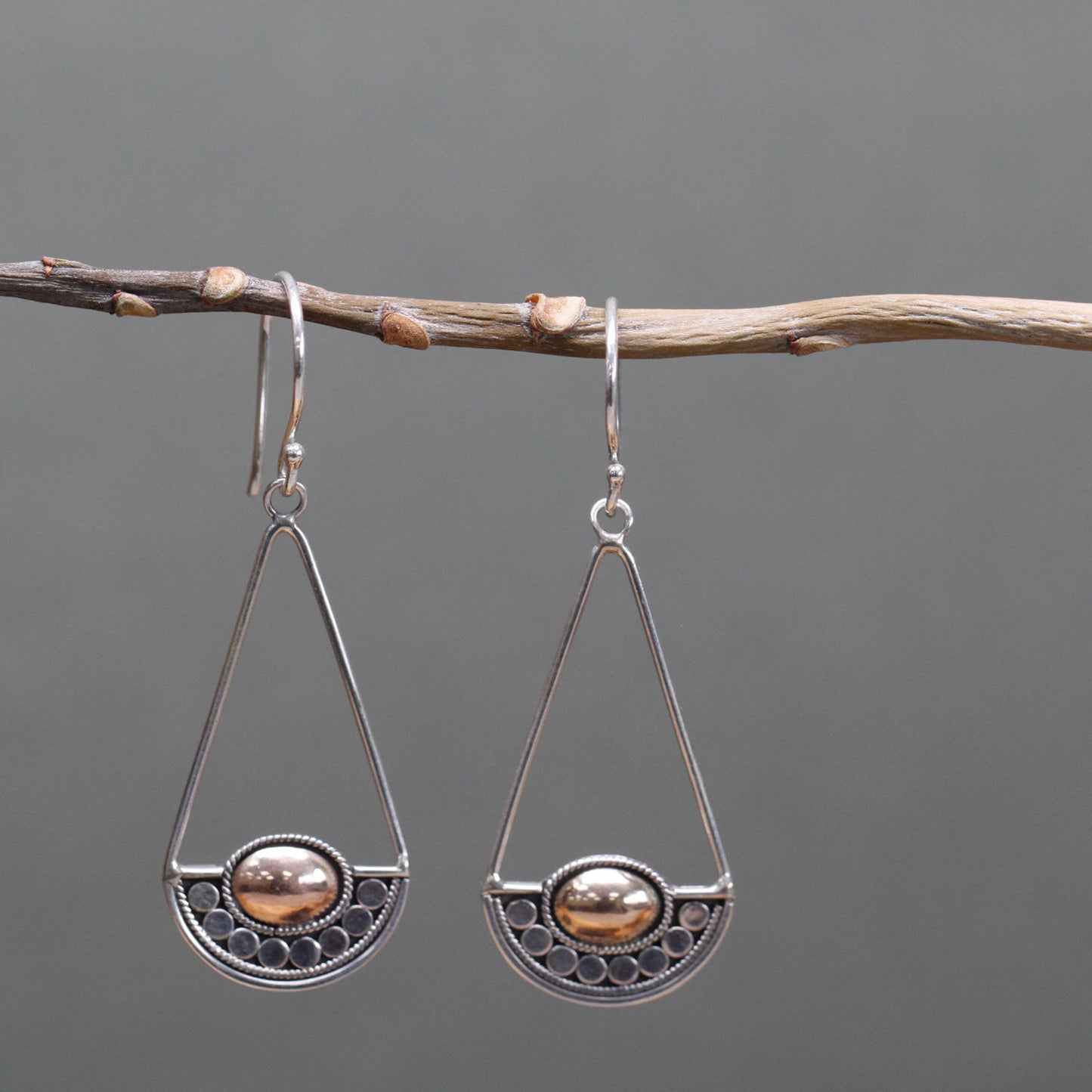 "Geometric silver earrings with balance-scale inspired design and central 18k gold oval, handcrafted in Indonesia."
