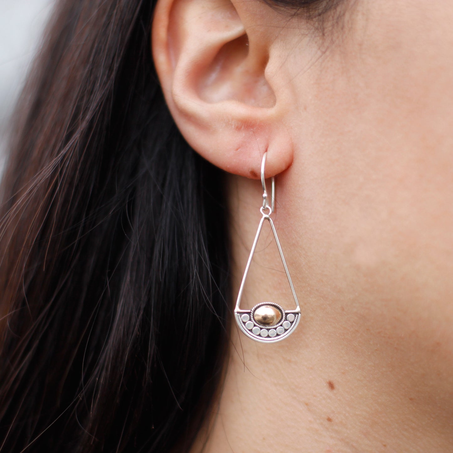"Geometric silver earrings with balance-scale inspired design and central 18k gold oval, handcrafted in Indonesia."
