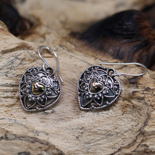 "Heart-shaped sterling silver earrings with mandala design and 18k gold heart centre, handcrafted in Indonesia."