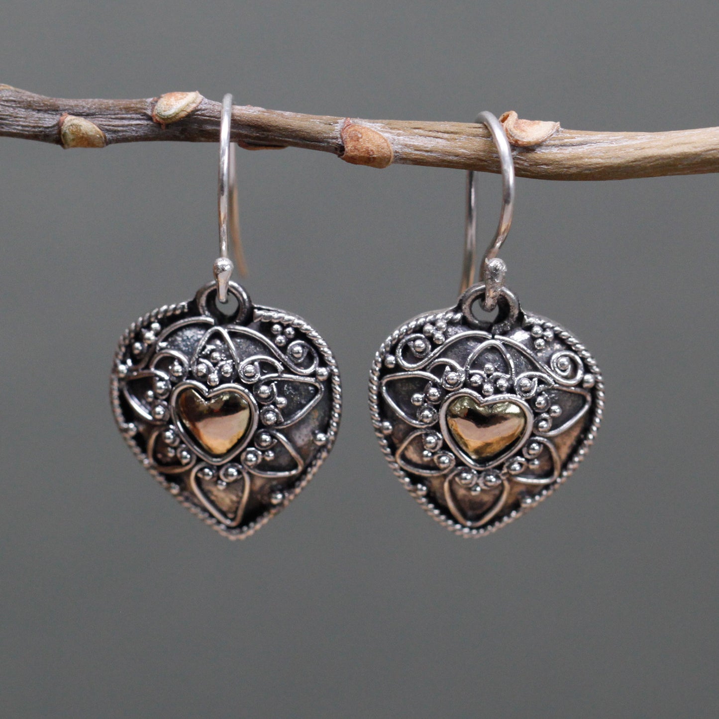 "Heart-shaped sterling silver earrings with mandala design and 18k gold heart centre, handcrafted in Indonesia."