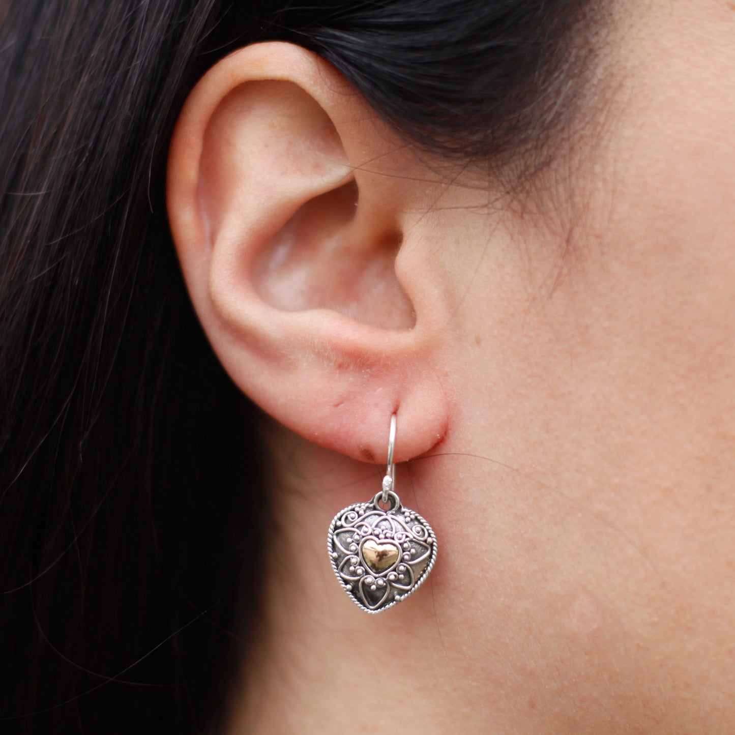 "Heart-shaped sterling silver earrings with mandala design and 18k gold heart centre, handcrafted in Indonesia."