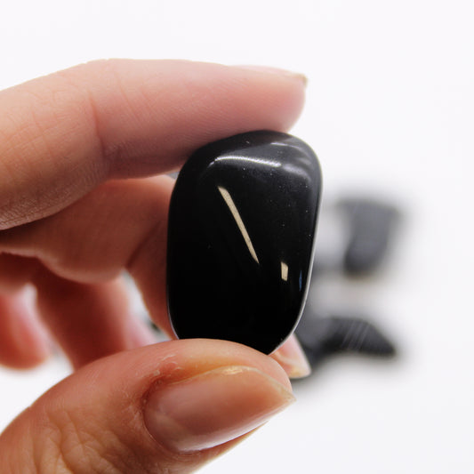 Polished black obsidian tumbled stone (10–25 mm), symbolising protection, grounding, and truth.