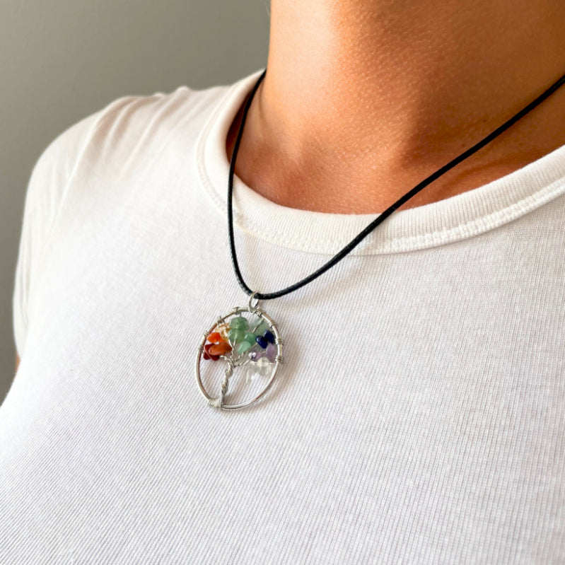 "Tree of Life Pendant featuring seven Chakra gemstones arranged in a rainbow design, crafted with silver wire on a black cord."