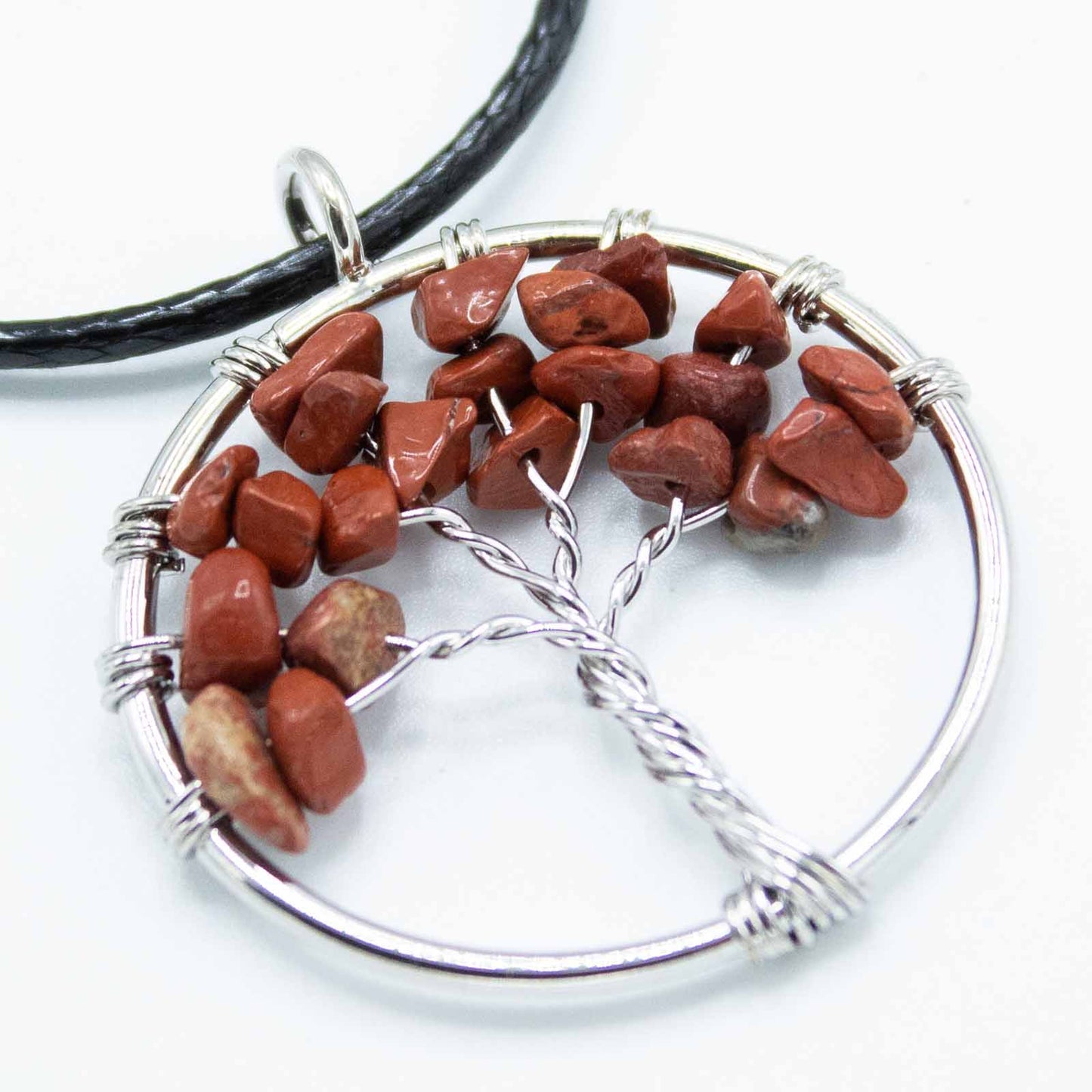 "Tree of Life Pendant featuring a deep red Jasper gemstone in a delicately wire-wrapped silver design, suspended on a black cord."