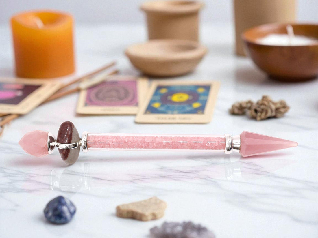 Crystal wand made from rose quarts, on white marble counter top with tarot cards, candles and crystals in the background