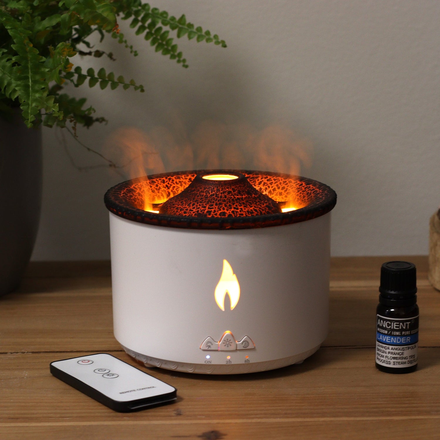 Electric aroma diffuser, top shaped like a volcano, body colour is white with a cutout on the front of a flame, all glowing with mist coming out of the top