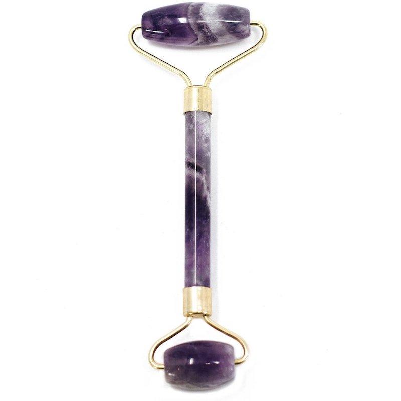 Crystal face roller, face roller made from amethyst crystal, large roller on one end and small roller on the other, purple in colour with gold metal brackets
