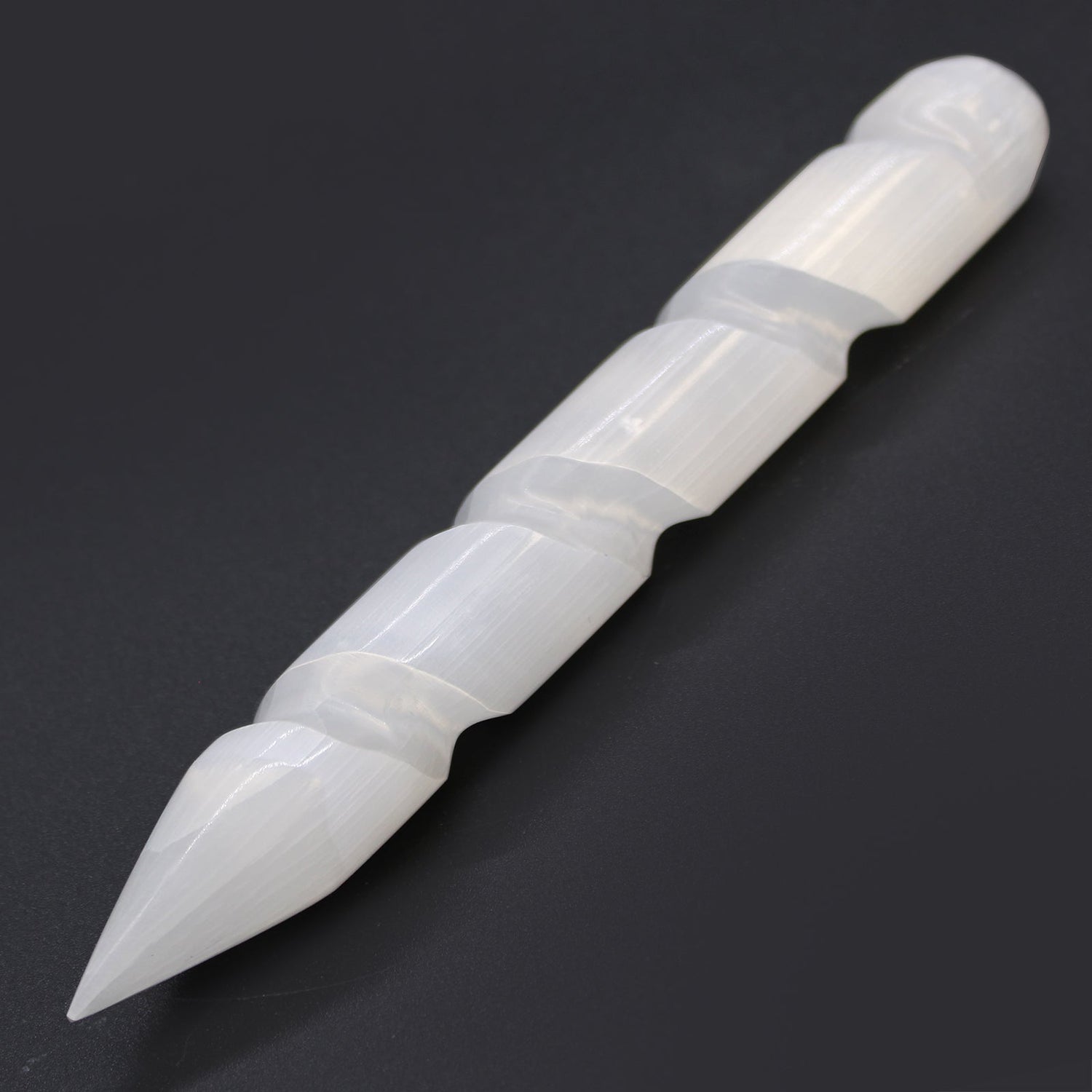 selenite crystal wand, pointed on one end and rounded on the other with a swirl carved into the body of the wand