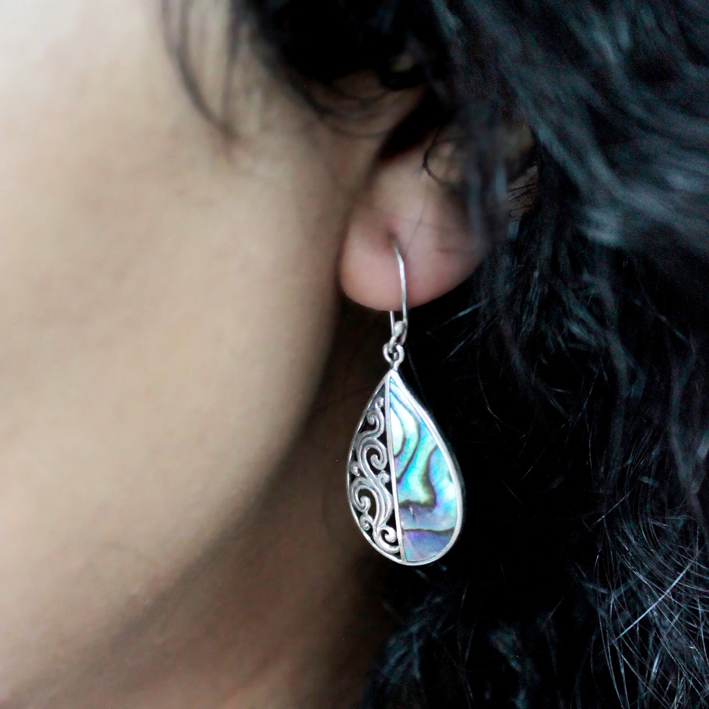 "Teardrop earrings with vertically split design: half abalone shell, half ornate silver swirl pattern, handcrafted in Bali."
