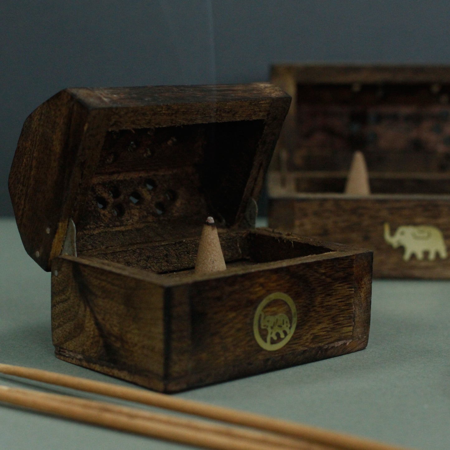 Mini mango wood incense cone box with brass elephant inlay and smoke vents. Ideal for compact spaces. Handcrafted and perfect for mindful moments.

