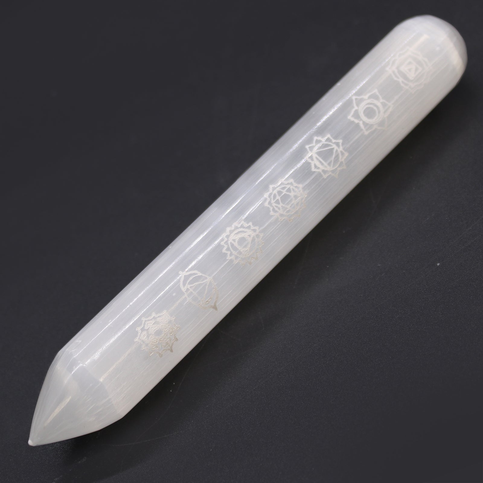 Polished Selenite wand engraved with 7 chakra symbols and a pointed tip, ideal for energy alignment, chakra healing, and spiritual cleansing rituals.

