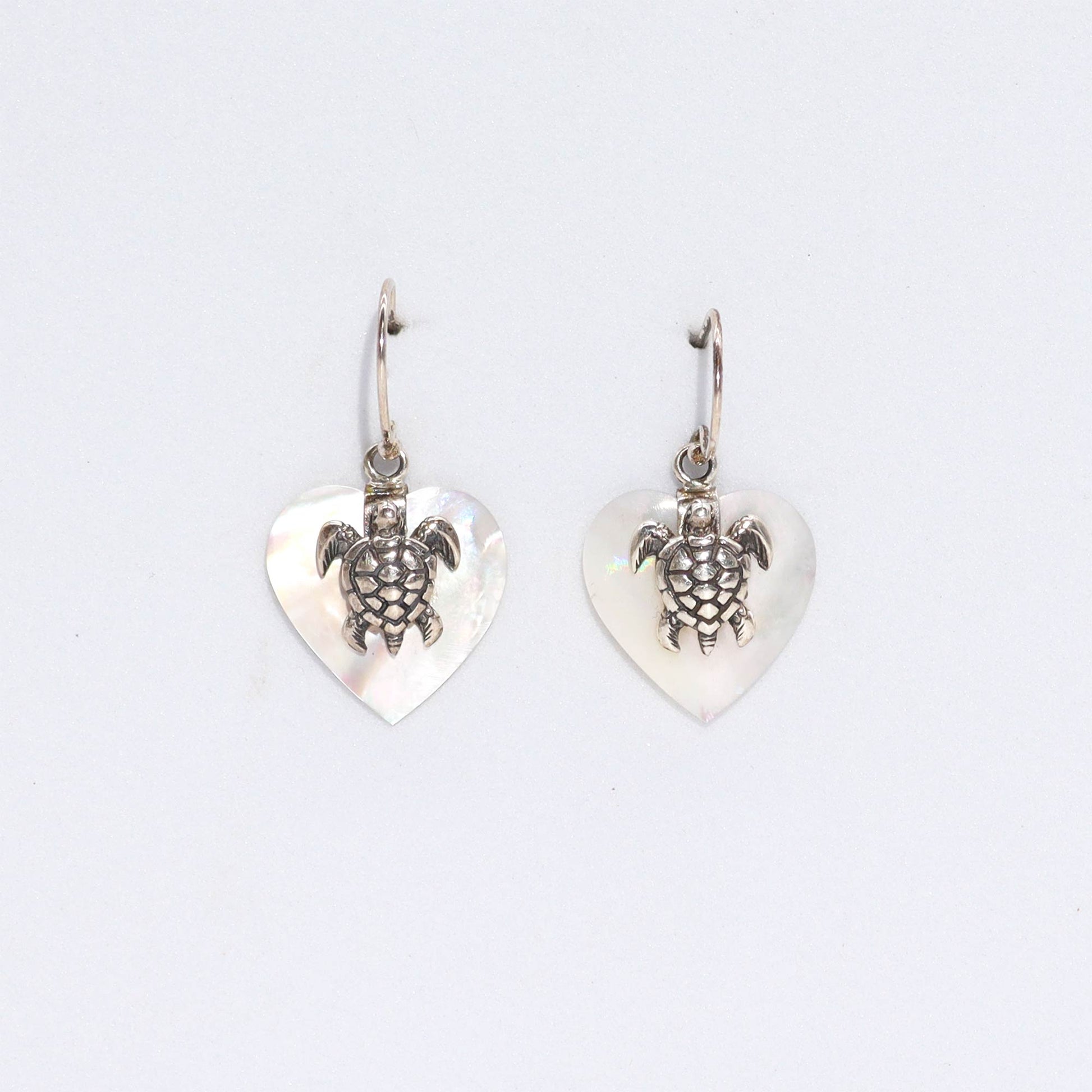 "Heart-shaped mother of pearl earrings with ornate sterling silver sea turtle overlay, handcrafted in Bali."