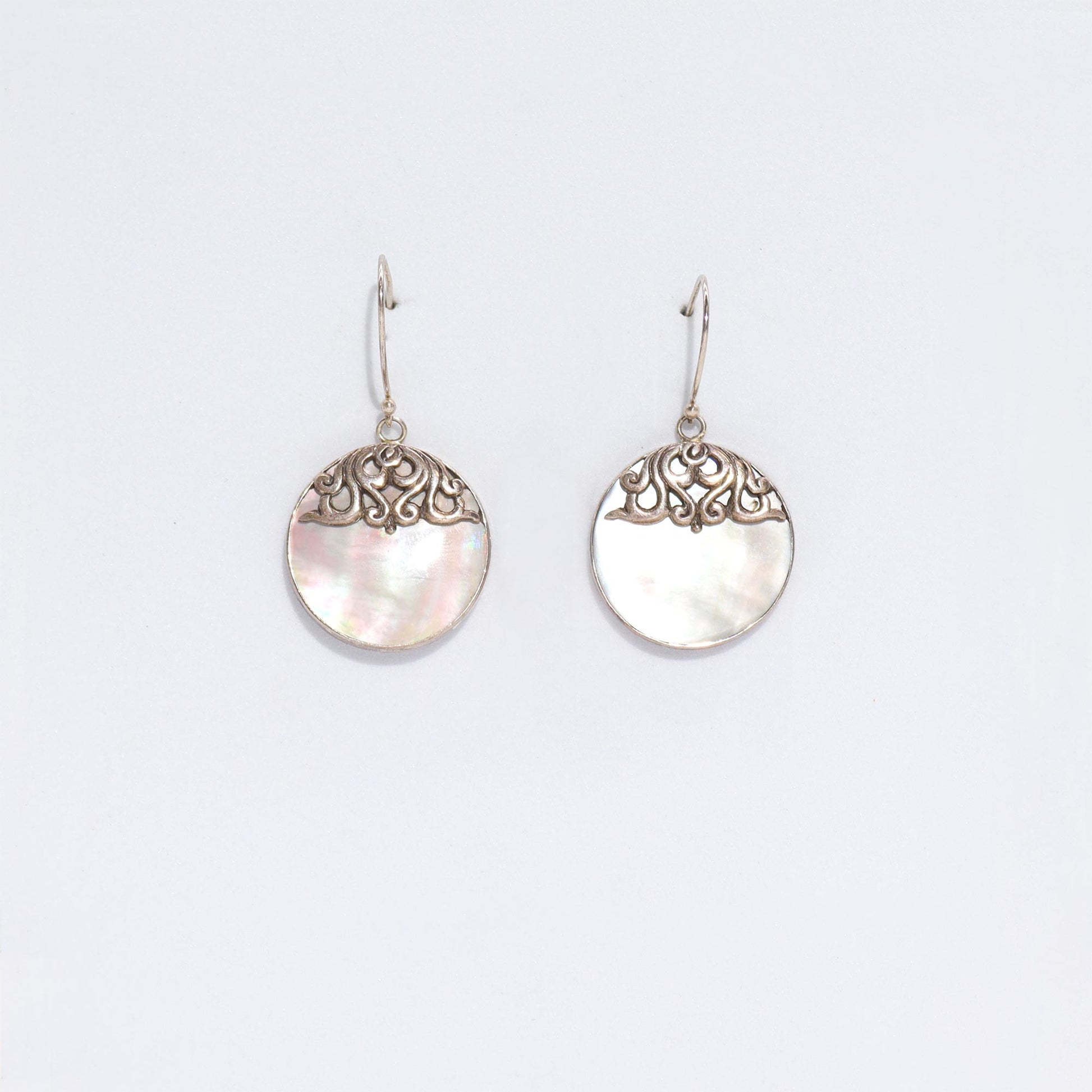 "Round mother of pearl earrings with ornate sterling silver swirl overlay and silver frame, handmade in Bali."