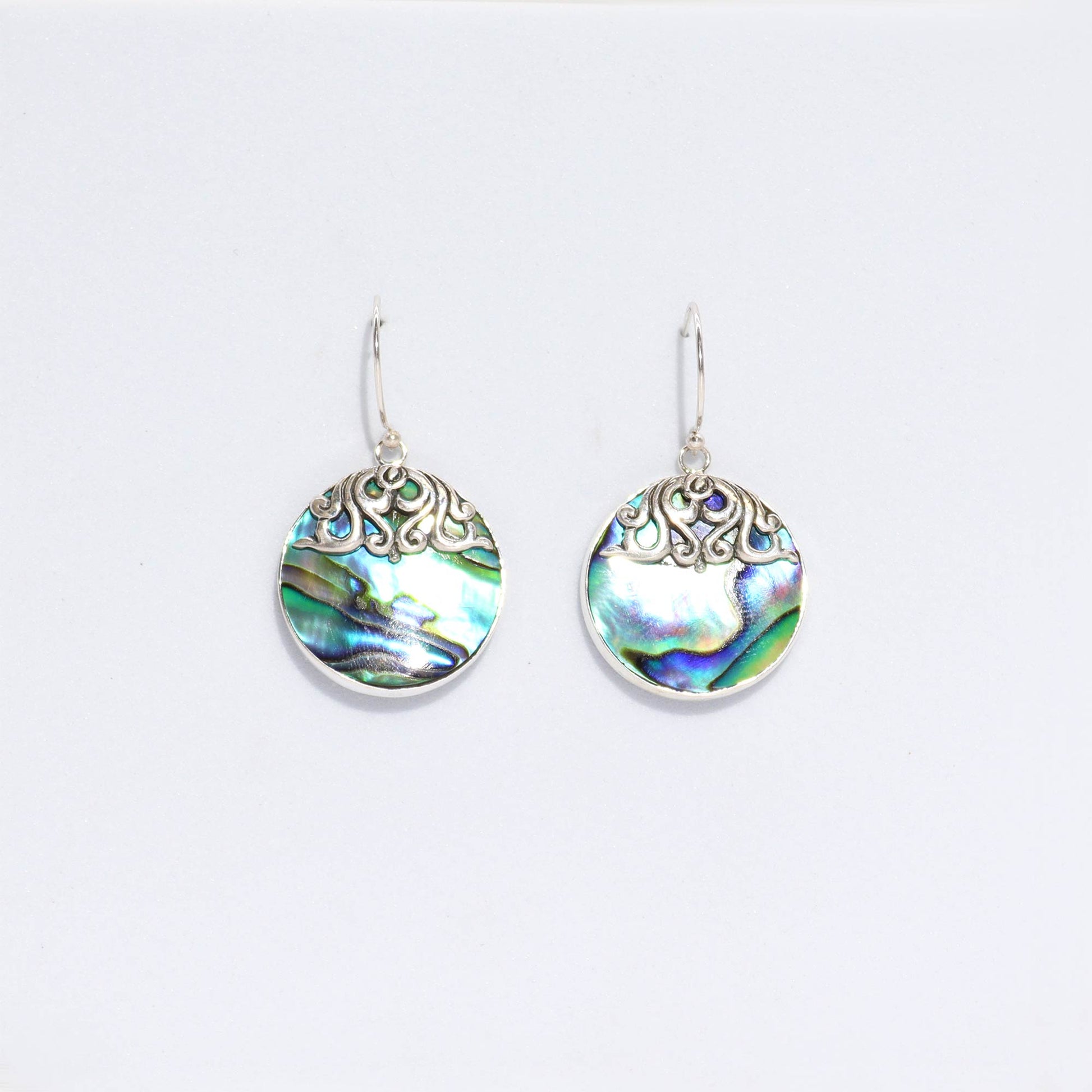 "Round abalone shell earrings with silver border and intricate swirl overlay at the top, handcrafted in Bali."