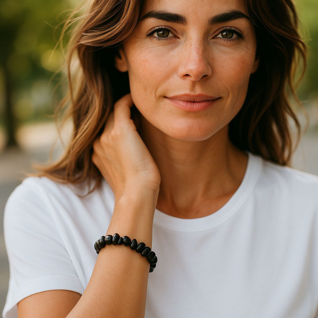 Black Agate chip stone bracelet with deep black stones, worn by a woman with brown hair and a white shirt, symbolising protection, grounding, and emotional resilience.
