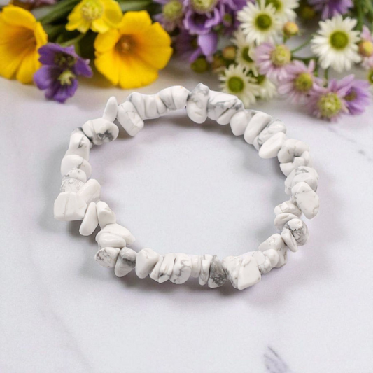 White Jasper chip stone bracelet with soft creamy stones, on a white marble table top with wild flowers in the background, symbolising peace, clarity, and emotional balance.
