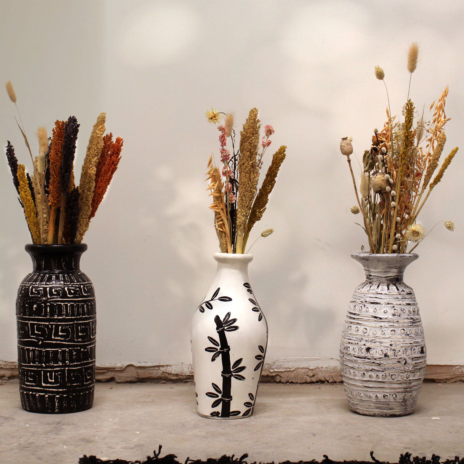 Natural terracotta vase with curved shape and black bamboo design – handcrafted in Lombok for dried flowers or decorative use.

