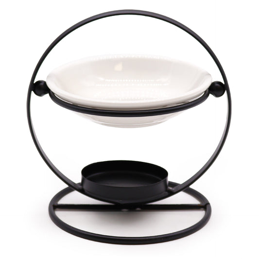 Modern oil burner with white ceramic dish suspended in a black metal hoop stand, designed for essential oils and tealights

