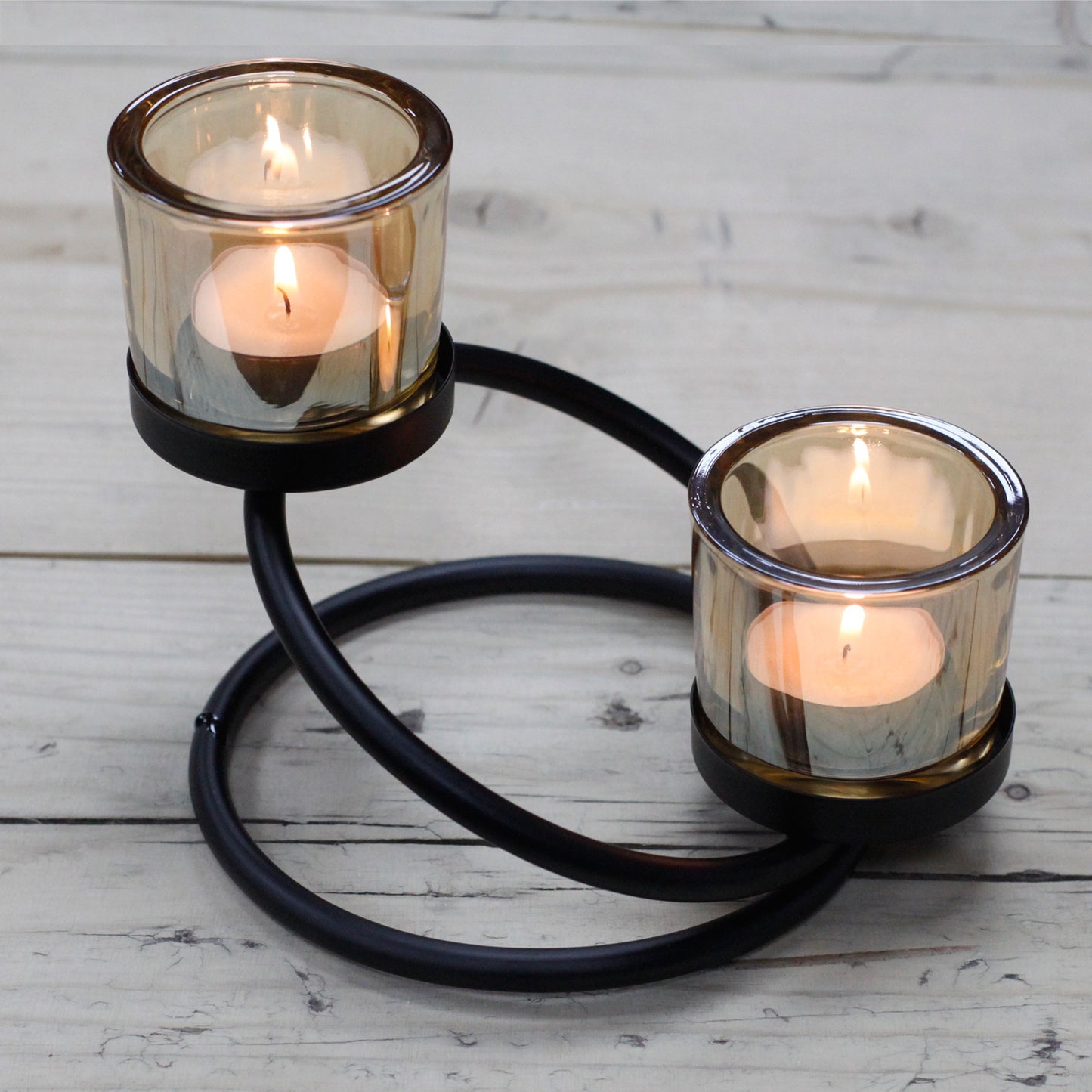 Double iron votive candle holder with circular swirl base and amber glass – decorative lighting piece