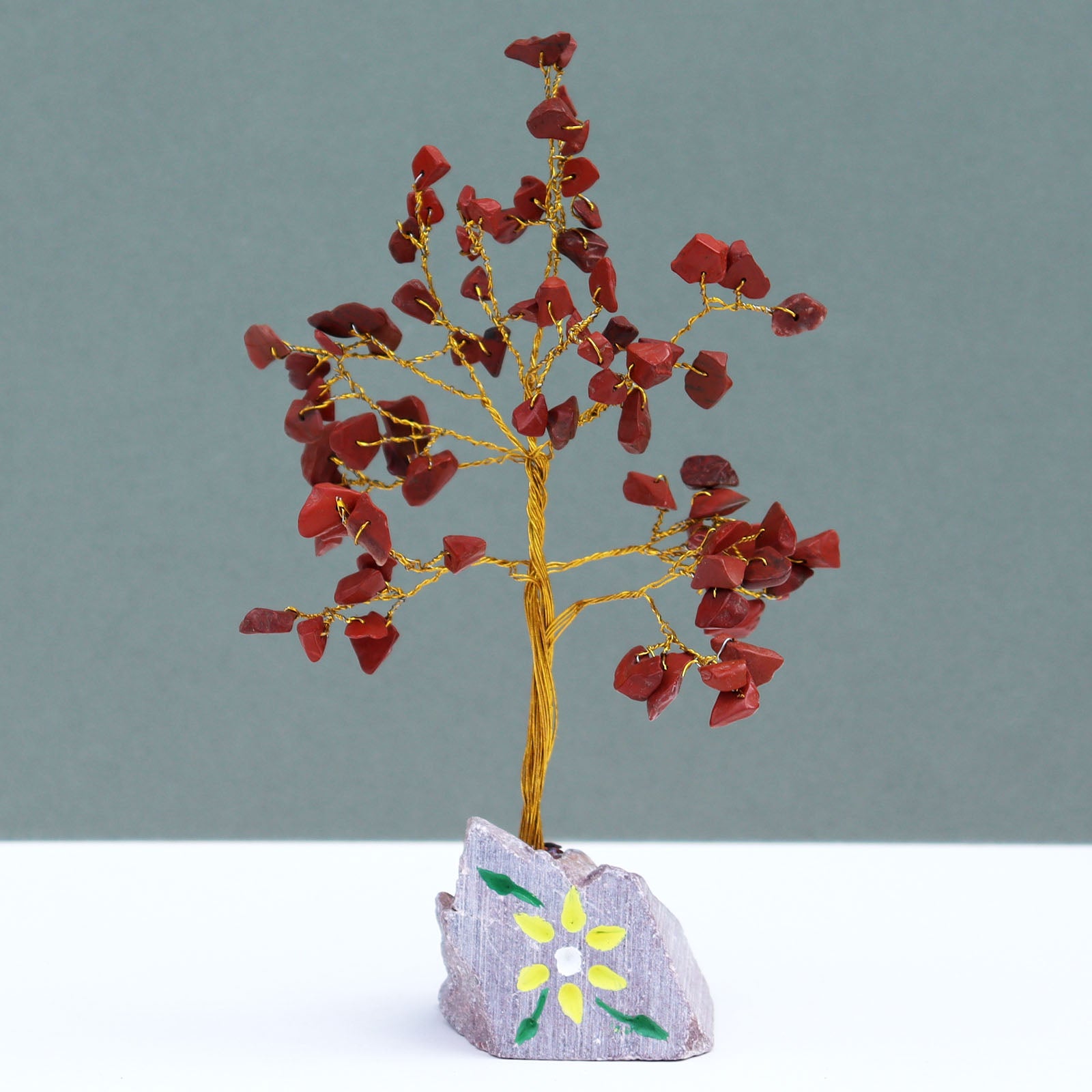 Red jasper crystal tree with 80 deep red gemstone chips on silver wire branches, mounted on a hand-carved and painted Indian stone base for earthy strength.

